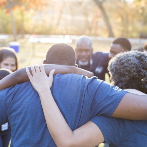 Large group of church volunteers huddle up before cleaning up their community.